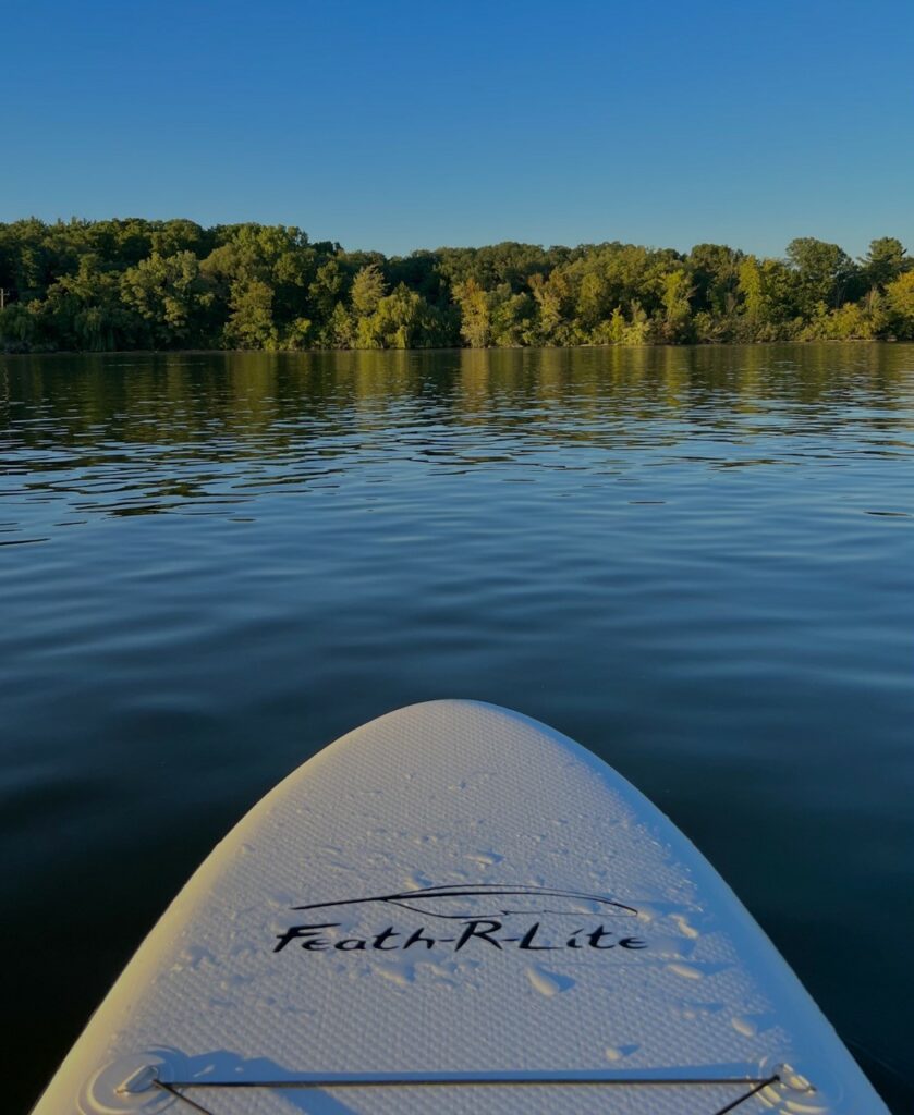 Inflatable Paddle Board Feath-R-Lite gliding through a lake during golden hour