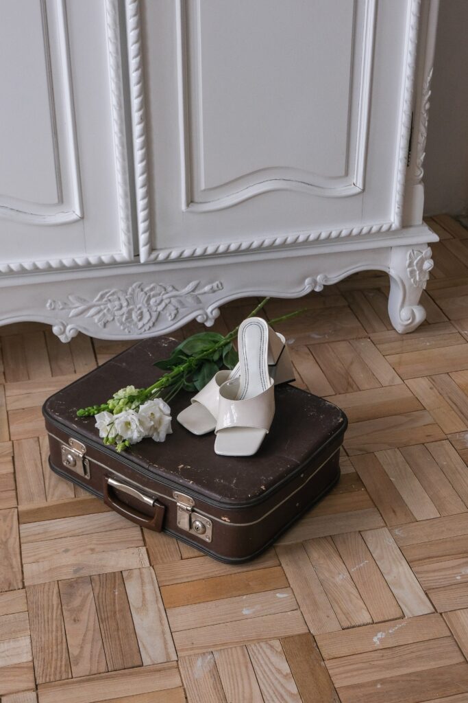 Travel Wedding Theme Aesthetic. Suit Case on the ground with white heels.